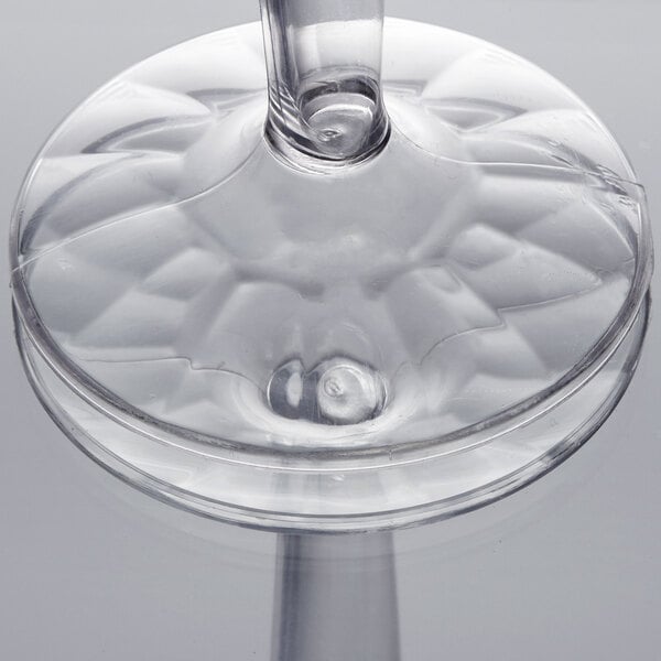 A close-up of a Fineline clear plastic champagne flute with a stem and circular design.
