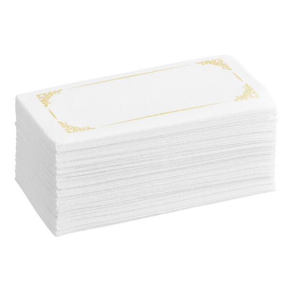 A stack of white linen-feel guest towels with a gold decorative border.