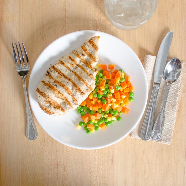 An Arcoroc white glass plate with chicken, carrots, and peas on it.