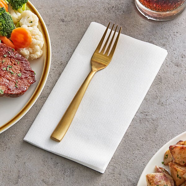 A fork on a Choice White Linen-Feel Dinner napkin next to a plate of food.