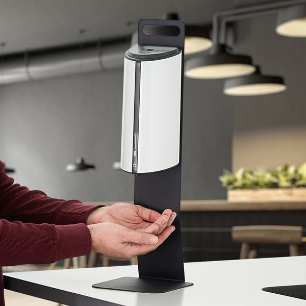 A person using a Noble Chemical hand sanitizer dispenser.