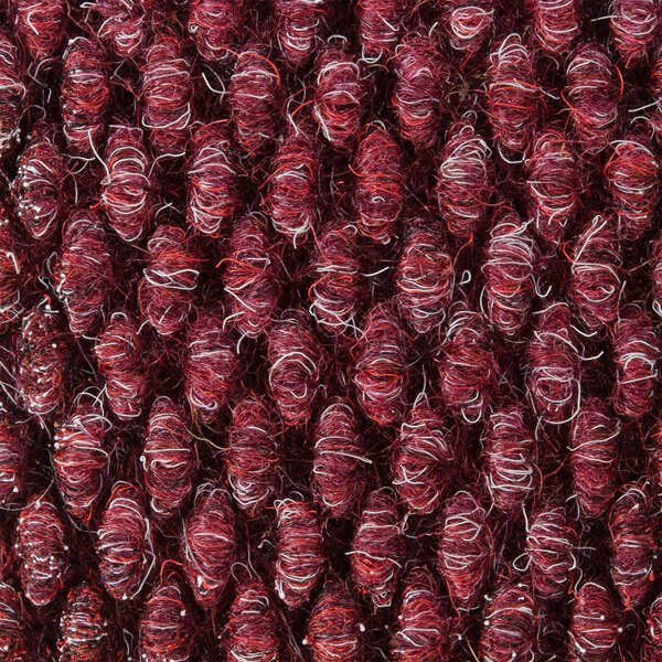 A close up of a burgundy carpet with a textured pattern.