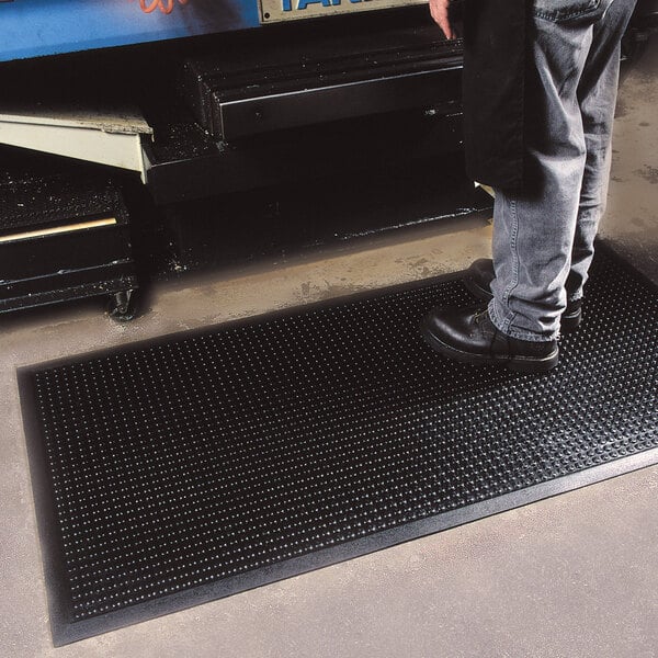 A man standing on a black Cactus Mat bubble-eze anti-fatigue mat.