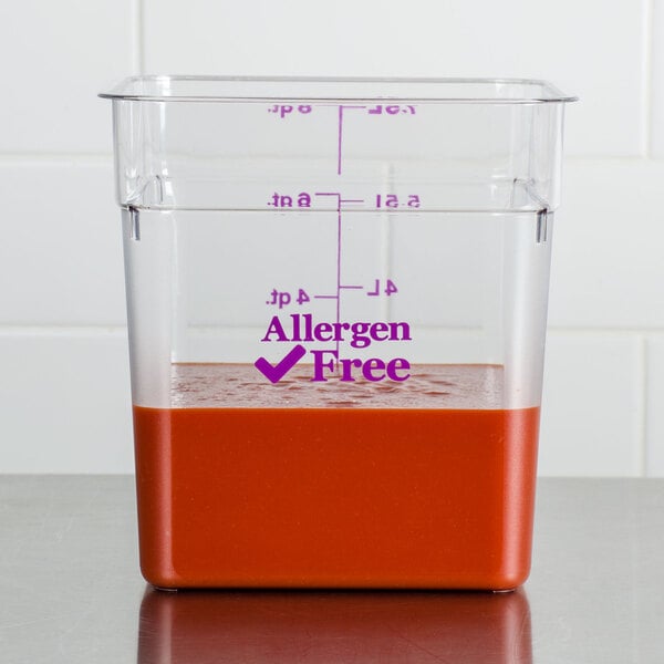 A Cambro clear polycarbonate food storage container on a counter with red liquid inside.