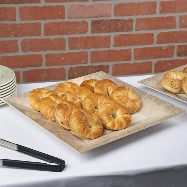 A table with a Thunder Group Jazz melamine plate of pastries and a knife.