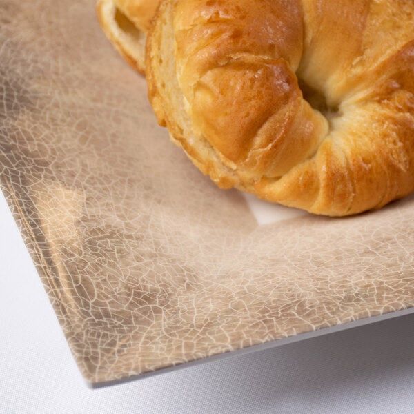 A close up of a bagel on a Thunder Group Jazz Square Melamine Plate with a crackle-finished border.