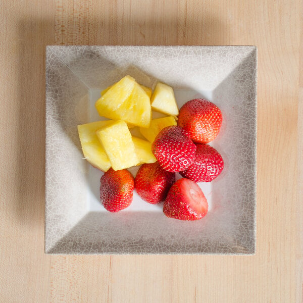 A Thunder Group Jazz melamine plate with a crackle-finished border holding pineapple and strawberries.