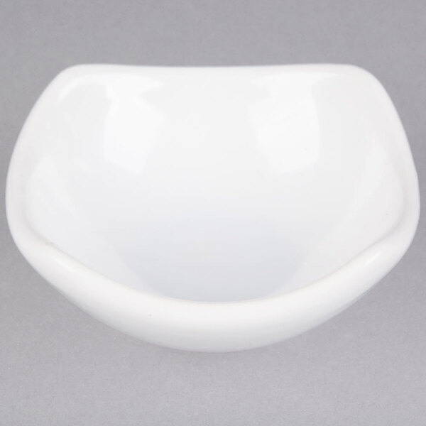 A white ceramic sauce cup with a curved edge.
