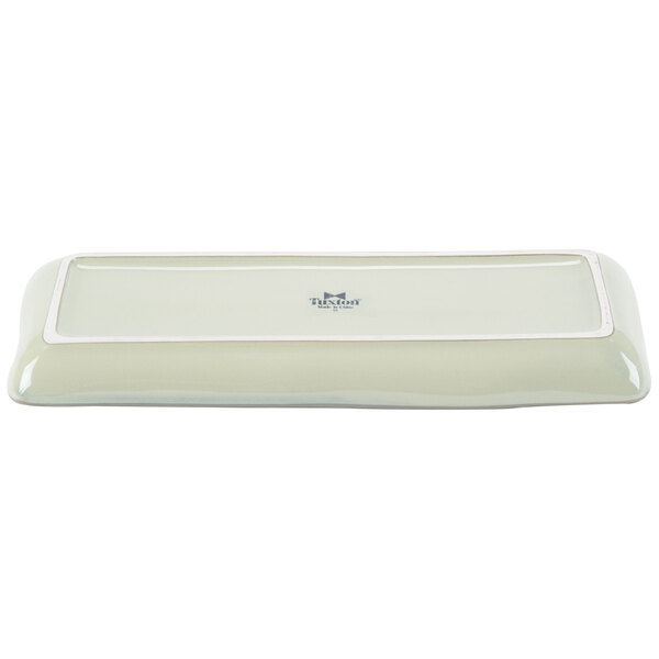 A white rectangular Tuxton china tray with a blue and white box.