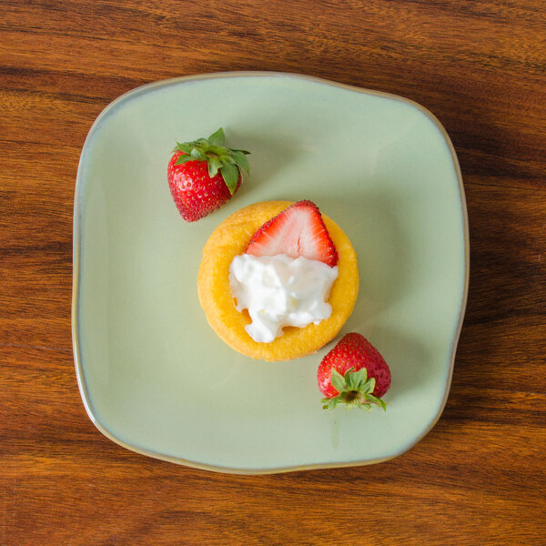 A Tuxton Artisan Sagebrush square china plate with strawberries and cream on it.