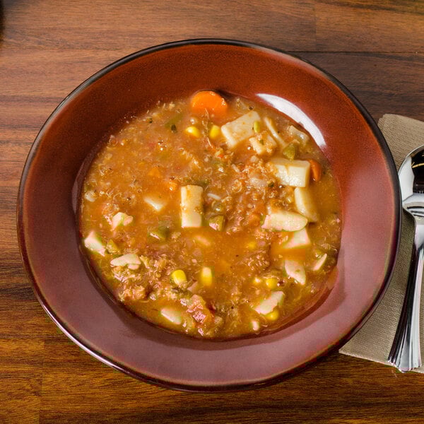 A Tuxton Artisan Red Rock china soup bowl full of soup with vegetables.