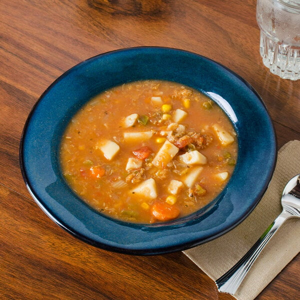 A Tuxton Artisan Night Sky china soup bowl filled with soup with meat and vegetables on a table.