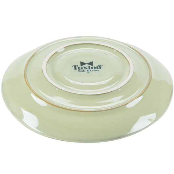 A white China saucer with a sagebrush green and black rim.