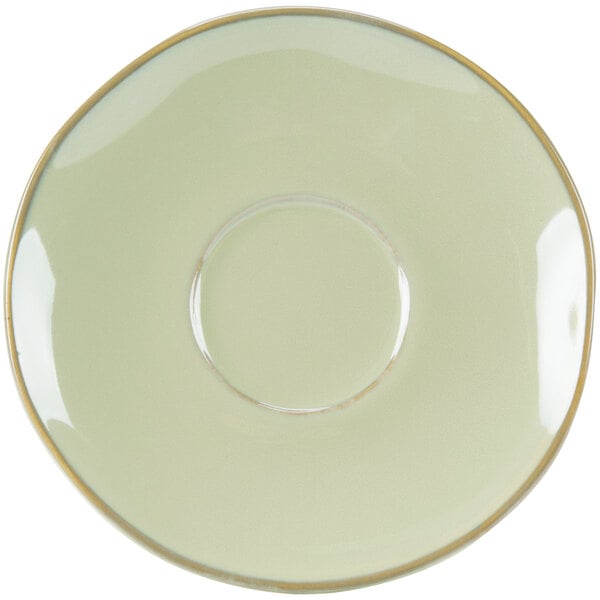 A white saucer with a gold rim on a green surface.