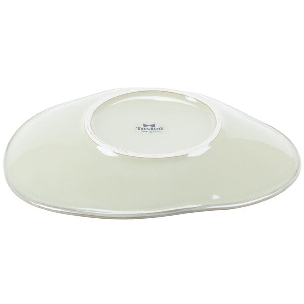 A white Tuxton China ellipse plate with a white rim.