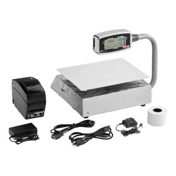 A digital price computing scale with a display tower, a thermal printer, power adapters, cables, and a roll of printer paper.