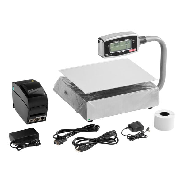 A digital price computing scale with a tower display, a thermal printer, a roll of paper, power adapters, and various connecting cables.
