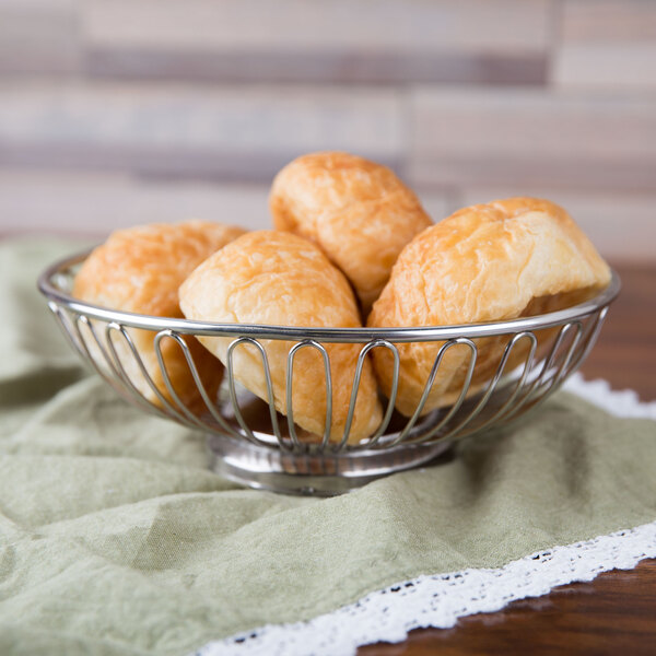 An American Metalcraft stainless steel oval basket filled with bread on a table.