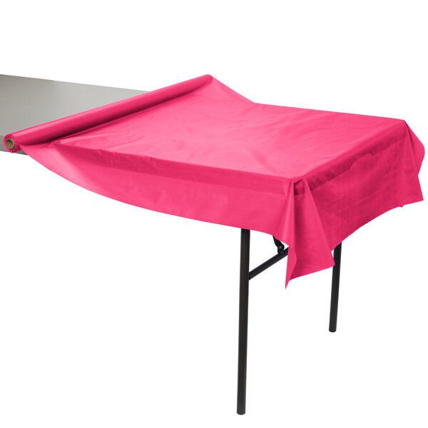 A Creative Converting hot magenta pink plastic table cover on a table.