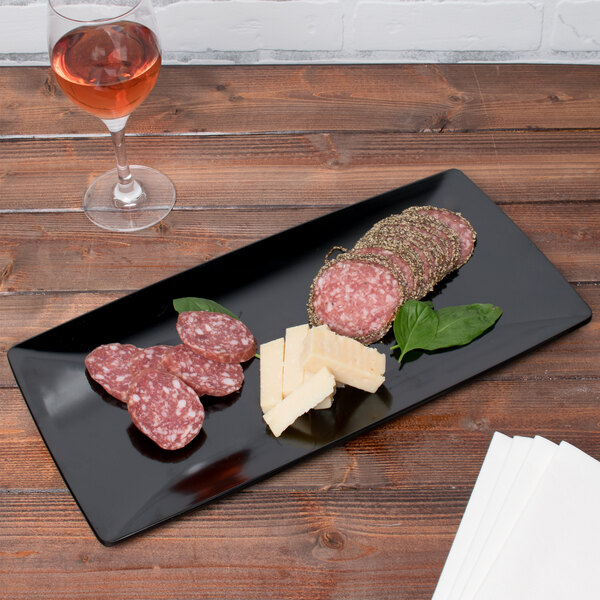 A black GET Siciliano tray with food on a table.
