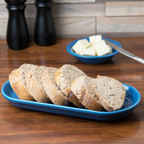 A Fiesta oval china bread tray in blue with slices of bread on it.