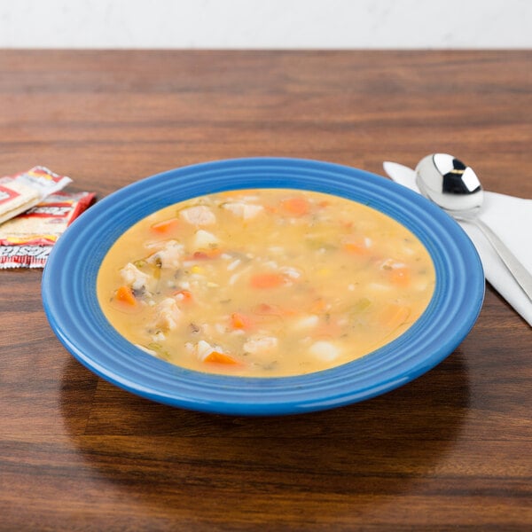 A Fiesta Lapis china rim soup bowl filled with soup on a table.