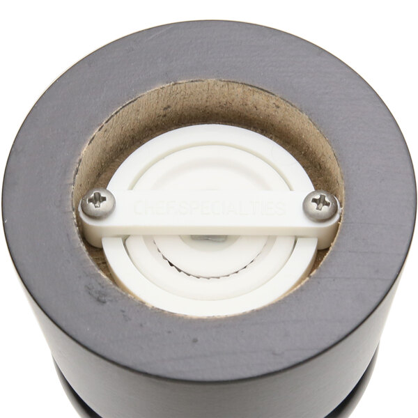A black circular pepper mill with a white circle in it.