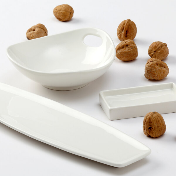 A rectangular Tuxton AlumaTux tray with 12 white ramekins, each with nuts in them.