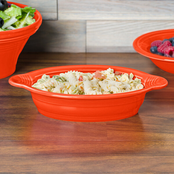 A Fiesta oval china baker filled with salad on a table.