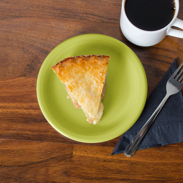 A slice of pie on a green Fiesta® appetizer plate next to a cup of coffee.