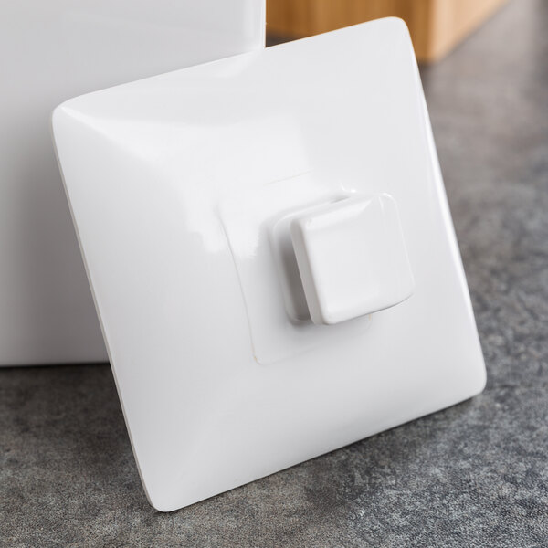 A white square Cal-Mil lid with a hole in it.