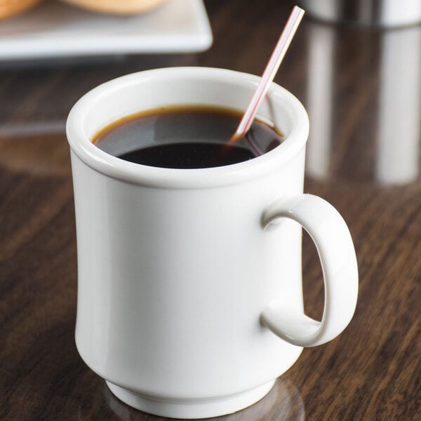 An ivory Tritan mug filled with coffee with a straw in it.