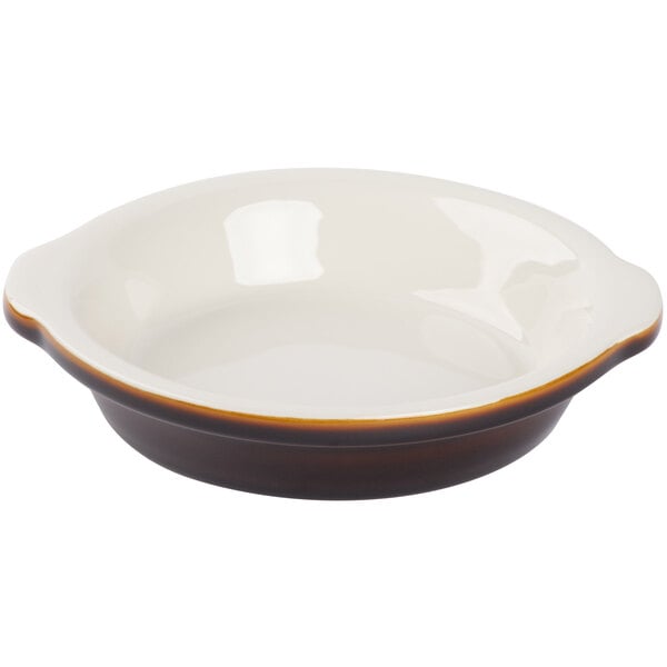 A white and brown Tuxton round au gratin dish with a handle.