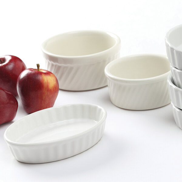 A close-up of a Tuxton Eggshell Swirl white ramekin filled with a red apple.