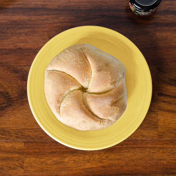 A Fiesta sunflower yellow bread and butter plate with a piece of bread on it.