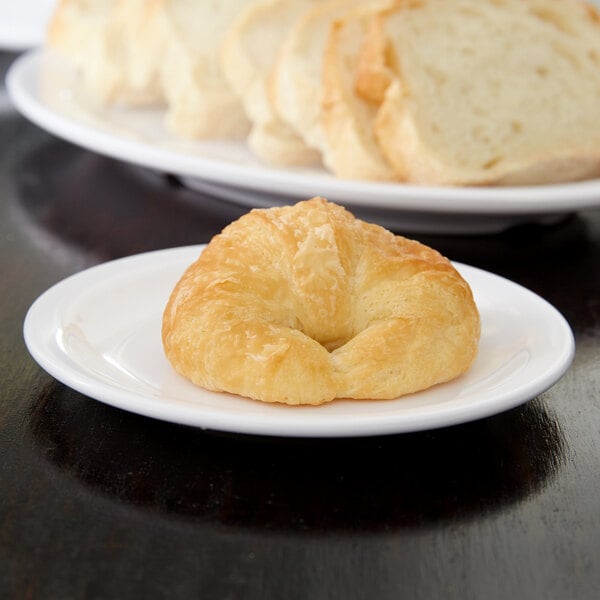 A Carlisle white melamine bread and butter plate with a piece of bread on it.