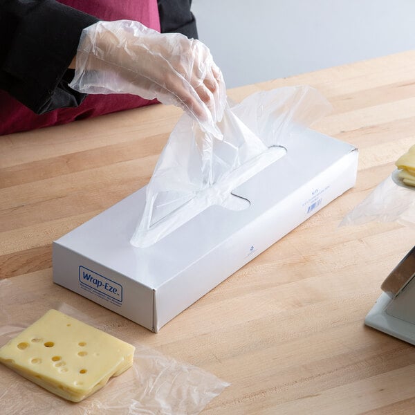 a person's hand in a plastic bag over a box of food