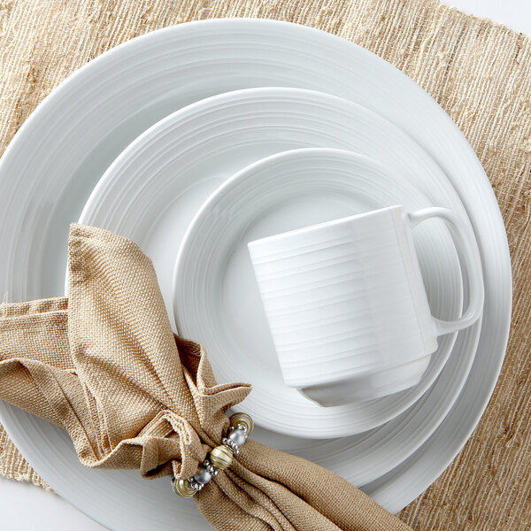 A Tuxton Pacifica bright white embossed china plate with a brown napkin on top.