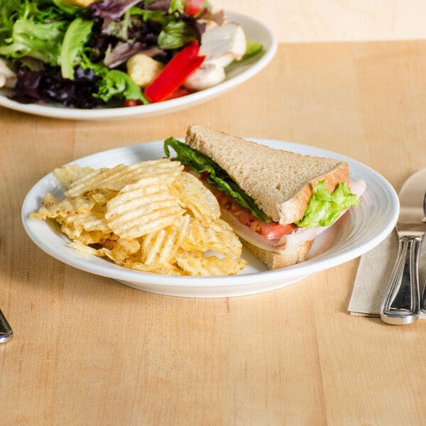 A Tuxton Pacifica bright white embossed china plate with a sandwich and chips.