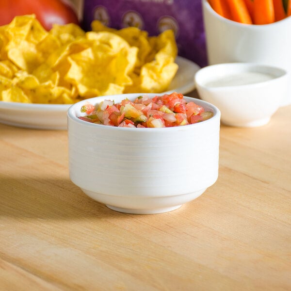 A Tuxton bright white china bouillon cup filled with salsa on a table.