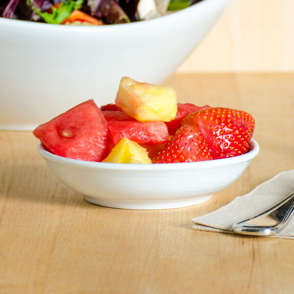 A Tuxton bright white china bowl filled with fruit on a table.