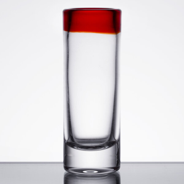 A close up of a Libbey shot glass with a red rim.