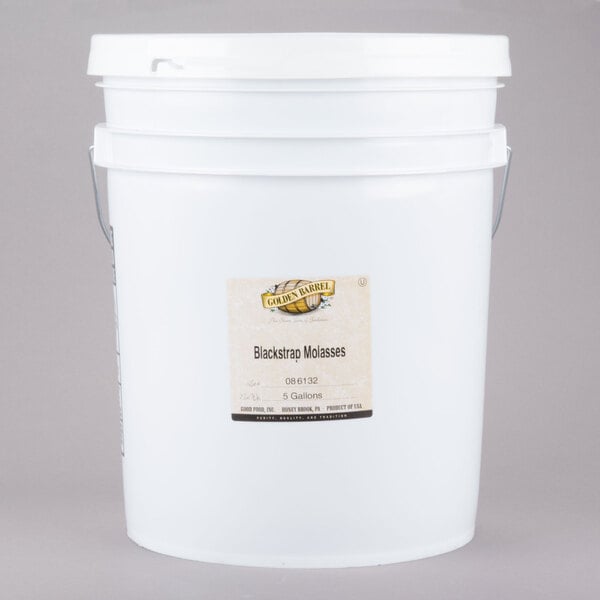 A white bucket with a label reading "Golden Barrel Sulfur-Free Blackstrap Molasses"