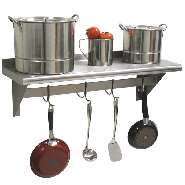 A stainless steel Advance Tabco wall shelf with pots and pans hanging from it.