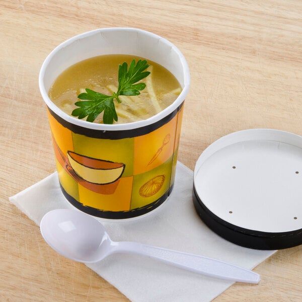 A Huhtamaki paper soup cup with a vented paper lid and a white spoon of soup on a table.