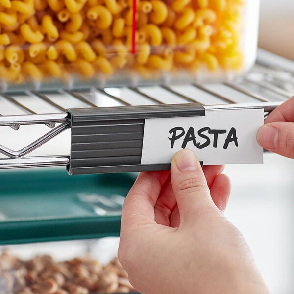 A person holding a Metro gray plastic label on a shelf.