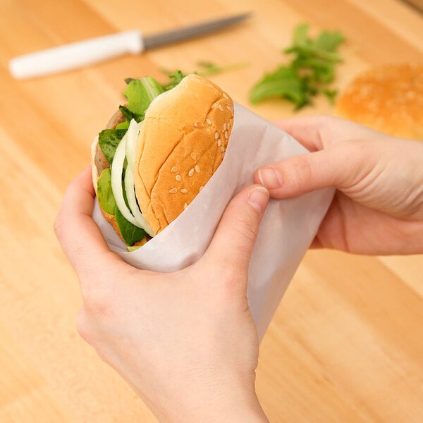 A person holding a sandwich wrapped in wet wax paper.