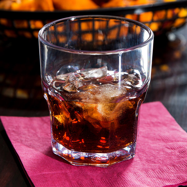 A Dinex clear plastic tumbler with ice and a brown drink.