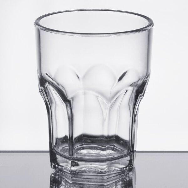 A Dinex clear plastic tumbler with a rim on a table.