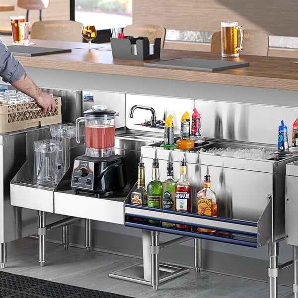 A man standing at a stainless steel Uni-Serv speed bar with a drink in his hand.